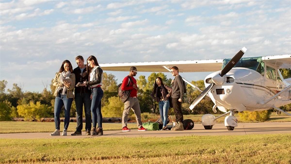 Pilots gathered near a high-wing aircraft