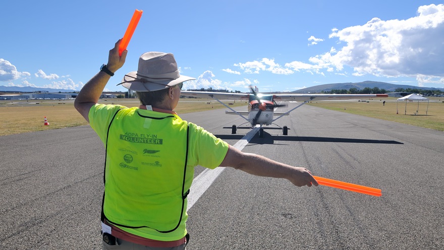 Volunteer Jerry McMillan of Prescott, Arizona, marshals an aircraft into the camping area at AOPA's Prescott Fly-In. Photo by Mike Collins.