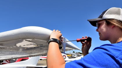 Kaitlyn Jones, an airframe and powerplant mechanic for Five Rivers Aviation, an FBO at Livermore Municipal Airport, installs a wingtip ADS-B unit during AOPA's Livermore Fly-In. Five Rivers installed several units on aircraft that had flown in for the event. Photo by Mike Collins.