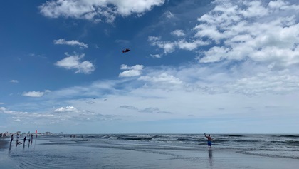 A fisherman waves at a U.S. Coast Guard MH-65 Dauphin search-and-rescue helicopter flying over the crowded beach. Photo by Paul Harrop.
