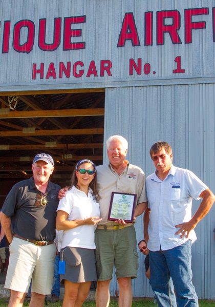 Greg Herrick (second from right) is presented the FAA Wright Brothers Master Pilot Award by AOPA President Mark Baker (left) and Antique Airplane Association President Brent Taylor (far right). Also pictured is Suzanne Herrick, Greg’s wife. Photo courtesy  of Brent Blue.