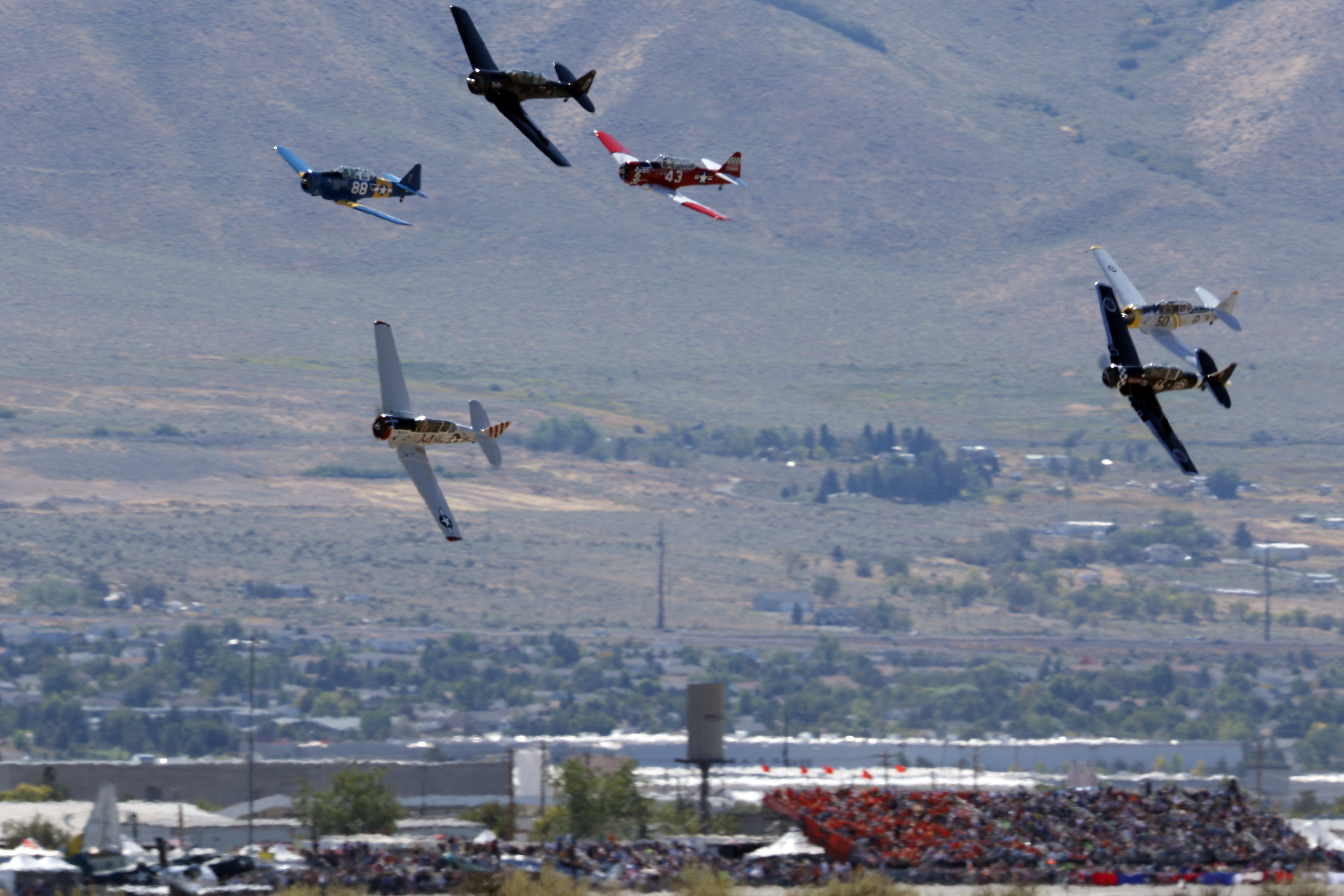 The T-6 class races past the crowd, with No. 14 AT-6B 'Baron's Revenge' flown by Chris Rushing in the lead, bottom, and Nick Macy in hot pursuit flying 'Six-Cat,' third from right, on a slightly higher line. Photo by Robert Fisher.