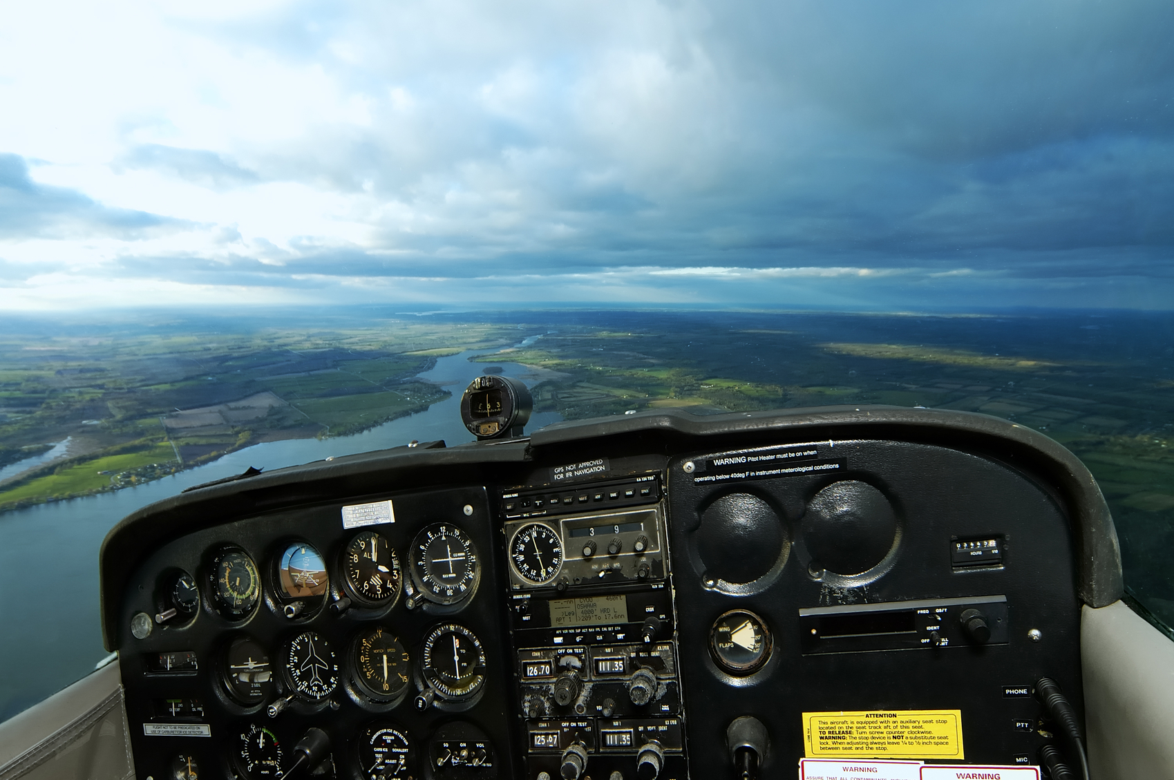 View from beyond the control panel of a cessna airplane with no roof or side windows in the frame to achieve an open canopy effect.  All text is generic warning notes and instrument readings. Clipping path for control panel embedded.