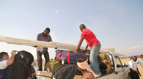 Jules Colastin (right, on top of truck) loads the truck with another driver.