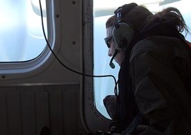Fisheries biologist Christin Khan scans the ocean through a bubble window in the NOAA Twin Otter.