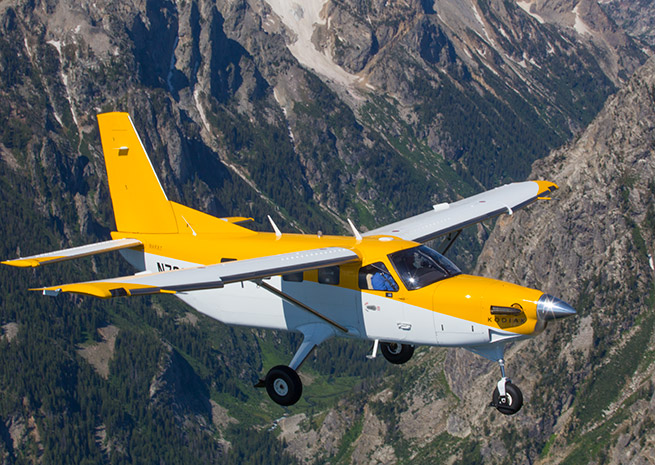 A Kodiak flies over the Tetons in July. Photo by Jim Moore