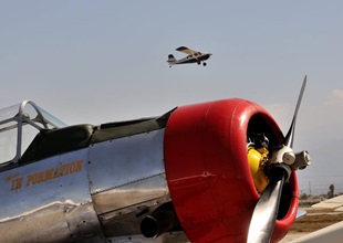 A departure climbs out above a polished T-6 in the static display area.