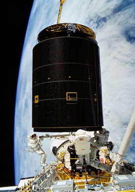 Heavy lifting may be required: on May 13, 1992, following the successful capture of the Intelsat VI satellite, three astronauts continue moving the 4.5 ton communications satellite into the space shuttle Endeavour's cargo bay. NASA photo.