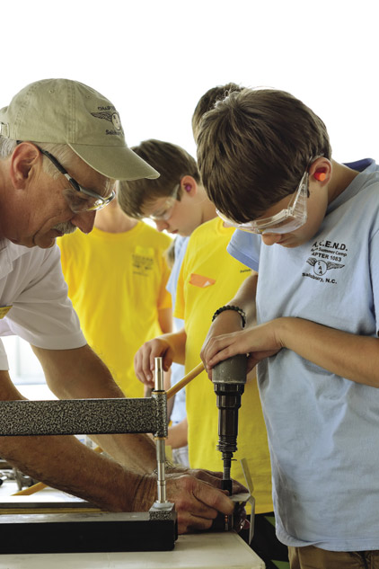 Roy Berrier helps a student drive a rivet 