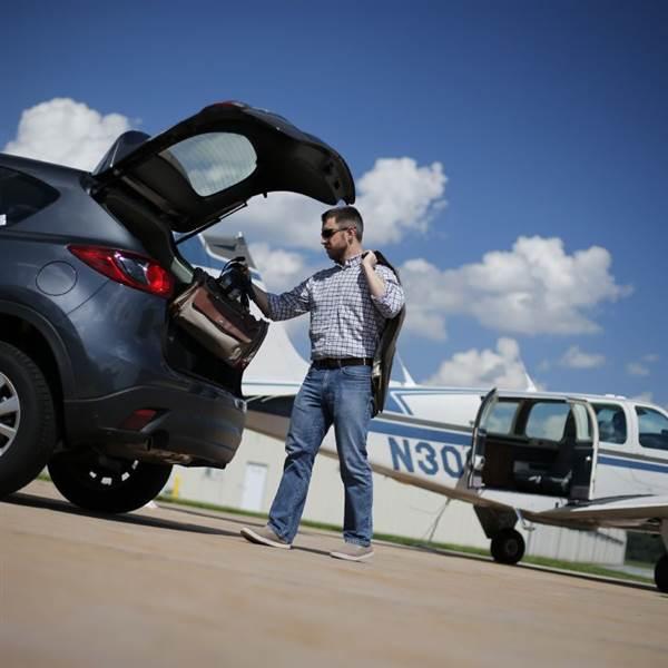 man unloading his car at an airport and preparing to load into his aircraft