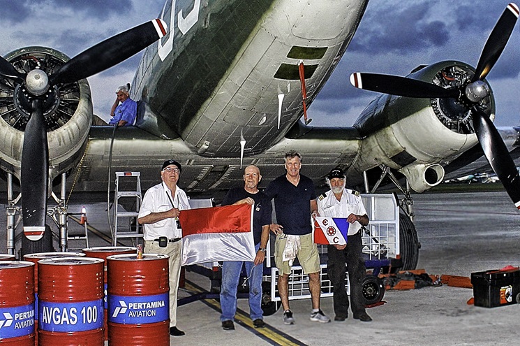 The "Buzz Buggy" crew is stuck in Surabaya, Indonesia, awaiting engine repairs. Shown left to right: Alan Searle of Australia, Dale Mueller of the United States, Tom Claytor of the United States, and Barry Arlow of Australia, and sitting on the wing, project founder Larry Jobe of the United States.