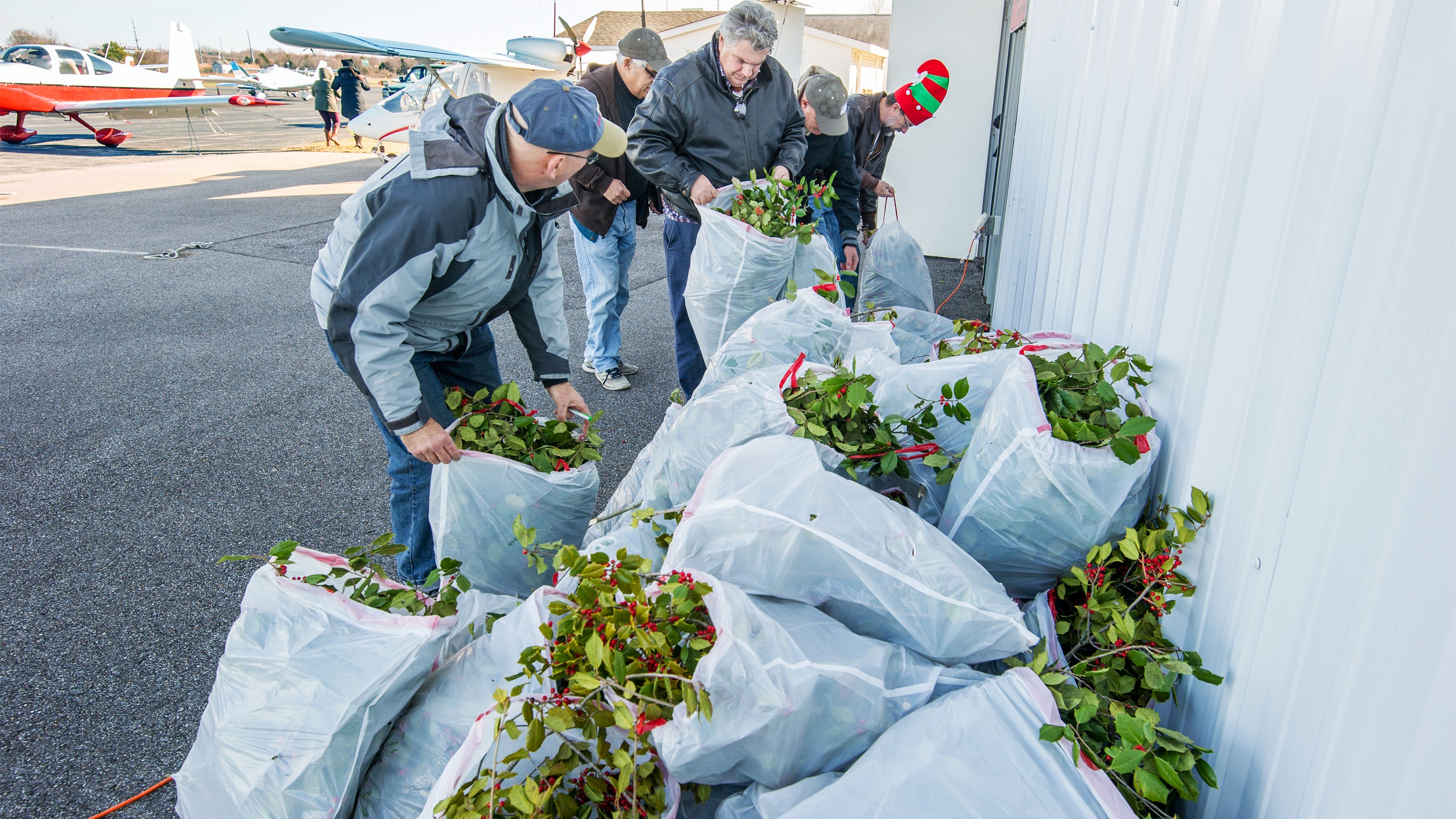 Pilots gather up holly branches during the annual Tangier Island Holly Run organized by Chesapeake Sport Pilot where aviators fly holly branches, presents, and school supplies to the small Virginia island in the middle of the Chesapeake Bay, Saturday, Dec. 10. Photo courtesy of Edwin Remsberg.