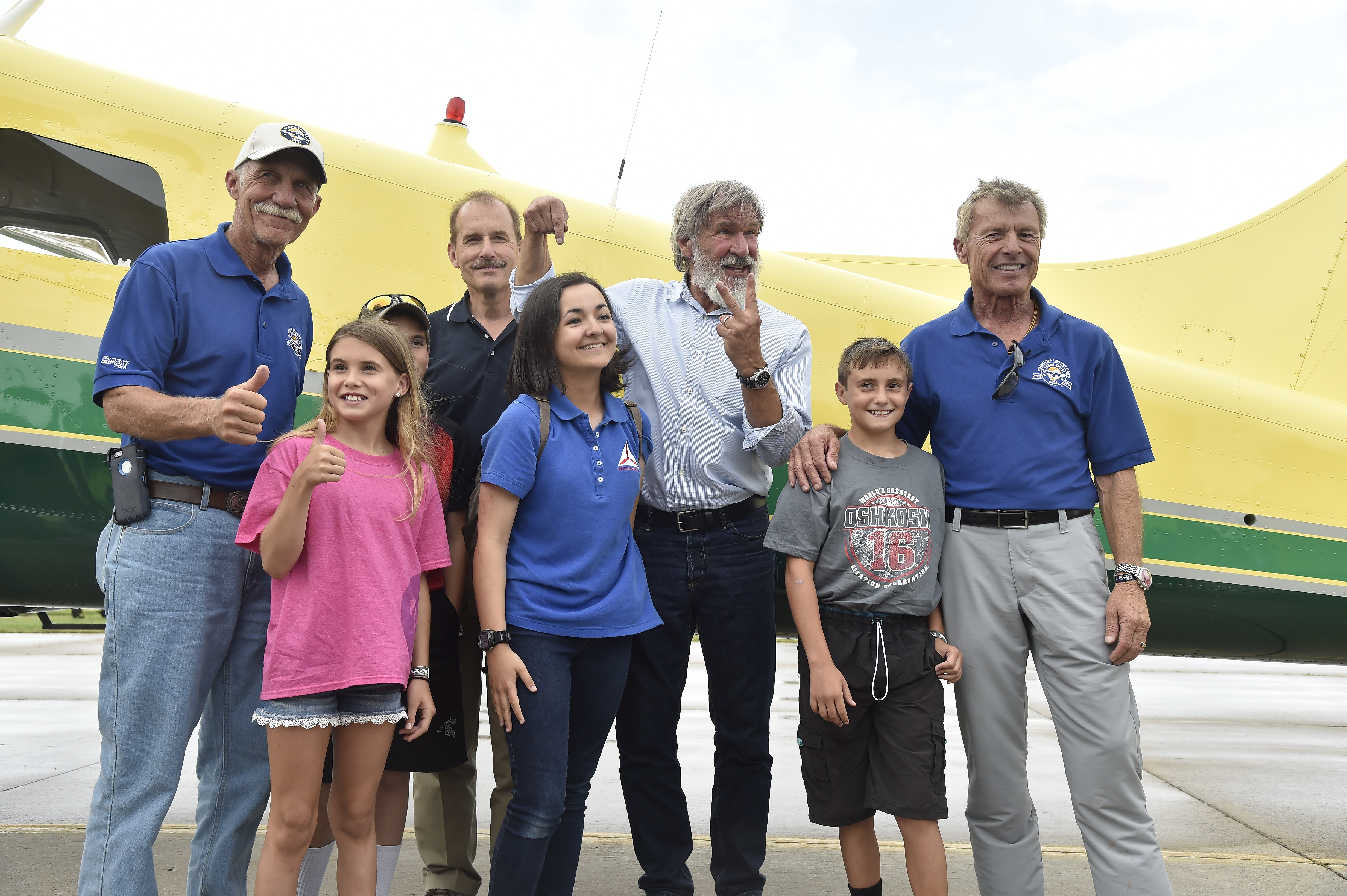 Actor and pilot Harrison Ford poses for photos with Jodie Gawthrop, the 2 millionth EAA Young Eagle, with airshow performer and current Young Eagle chairman Sean D. Tucker and other Young Eagles and pilots during EAA AirVenture at Wittman Regional Airport in Oshkosh July 28. Photo by David Tulis.