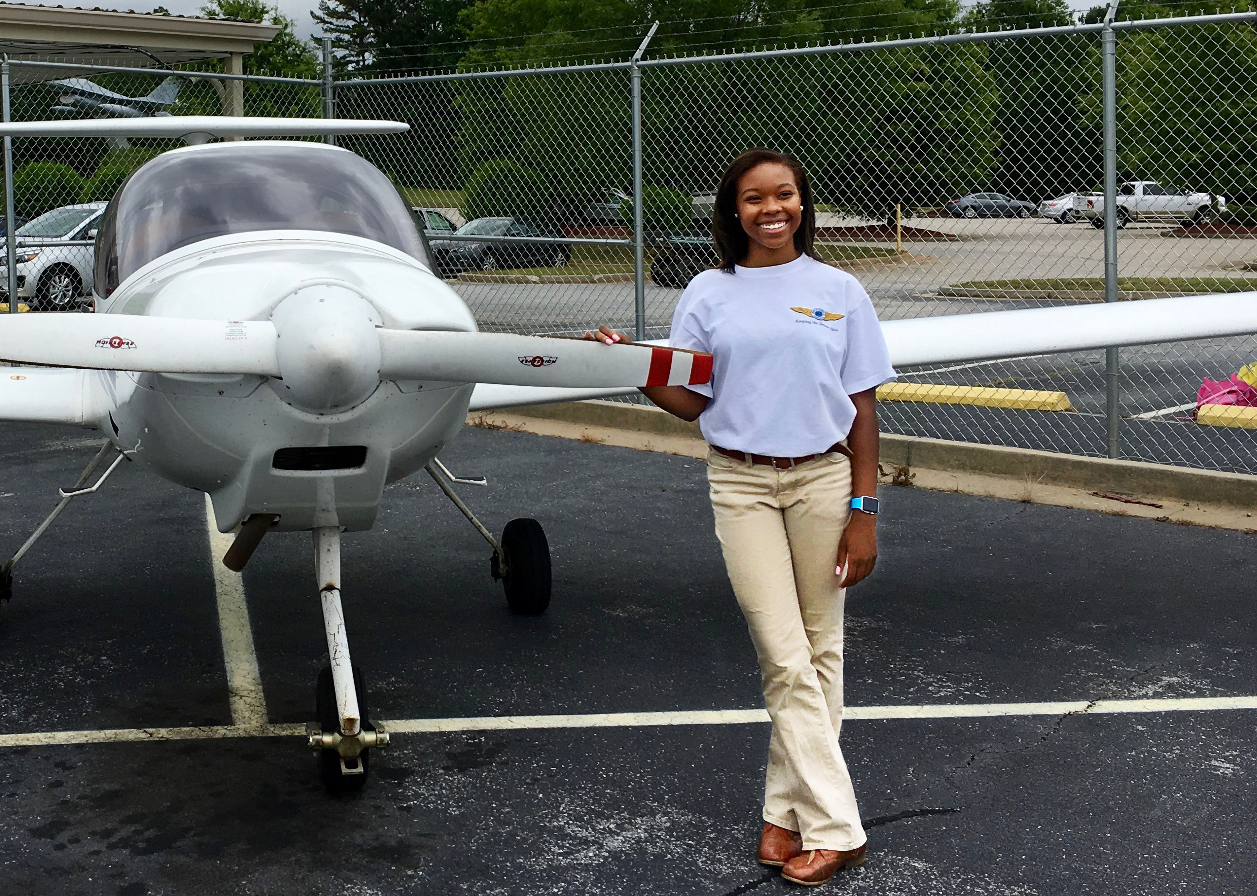 High school student Tyniyah Harris shown with a training aircraft.