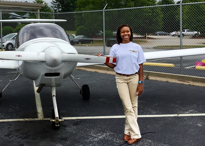 High school student Tyniyah Harris shown with a training aircraft.