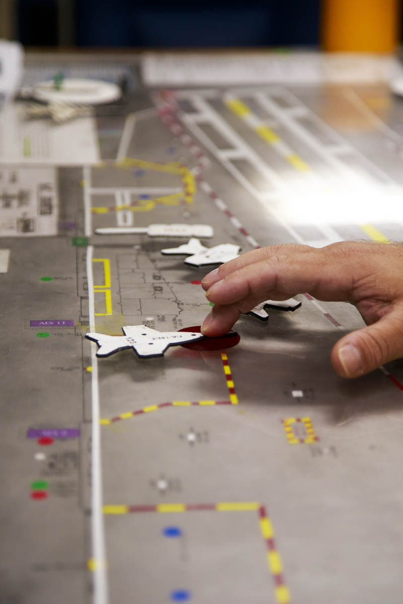 The 'Ouija board' is low-tech, but highly effective in keeping track of where aircraft and other equipment is on the busy flight deck. The aircraft cutouts and the board are to scale, so if it fits on the board, it will fit on the deck.