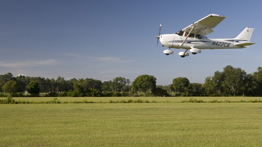 A pilot flies his Cessna 172 Skyhawk low over the grass at Bob White Airport in Zellwood, Florida, to check the condition of the runway.