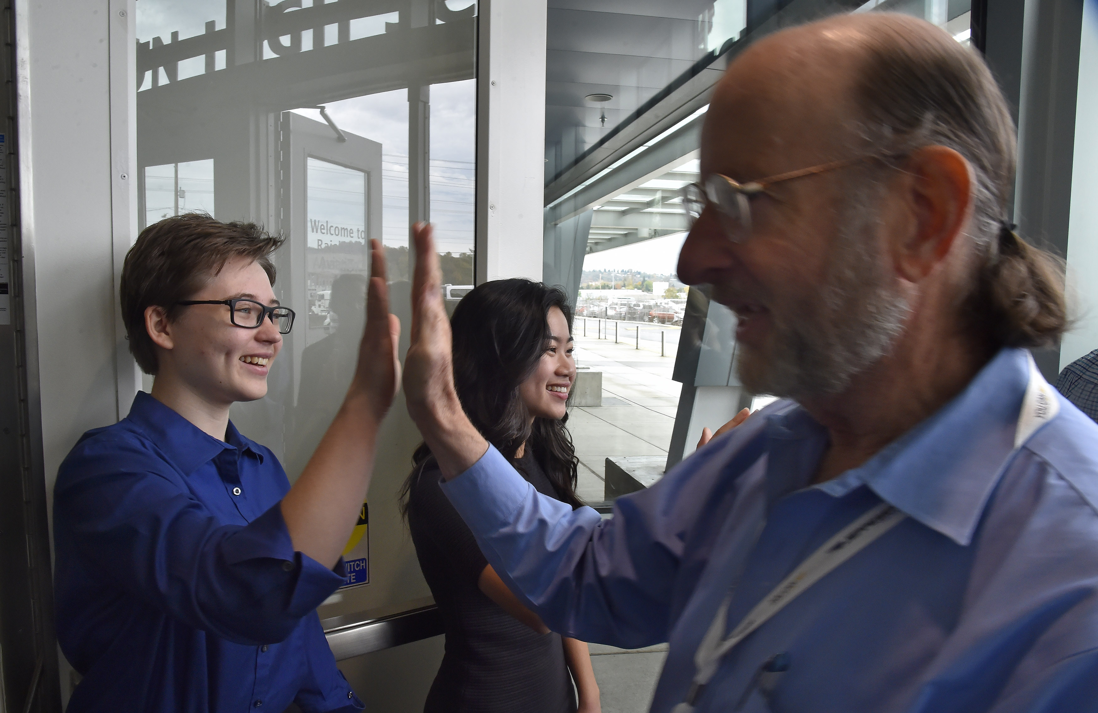 Raisbeck Aviation High School students greet AOPA High School Symposium attendees with a high-five during a tour of the facility in Seattle, Nov. 7. Photo by David Tulis.