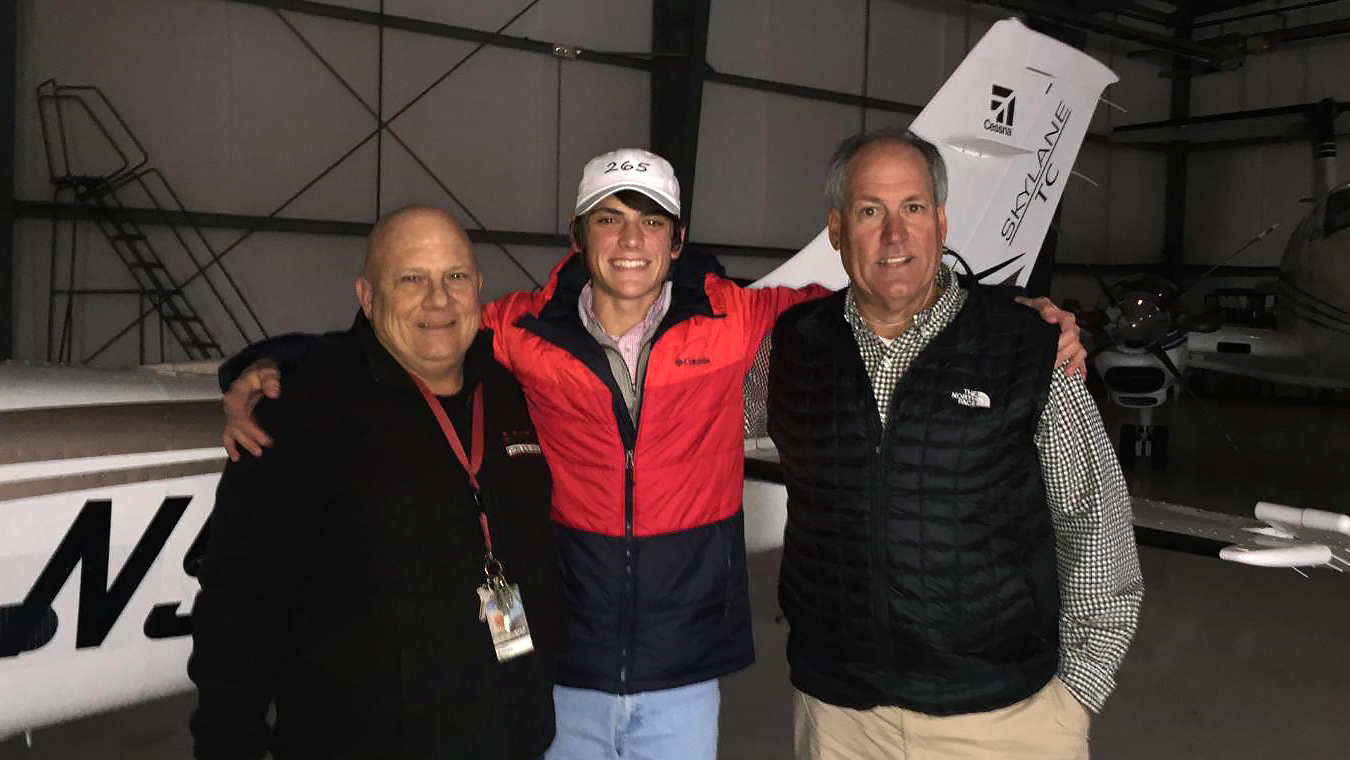 Benson Williams (center) embraces his flight instructor Brian Morgan (left) and father C. Allen Williams (right). Williams earned his private pilot certificate and instrument rating on his seventeenth birthday and followed up days later with his multiengine rating. Photo courtesy of C. Allen Williams.