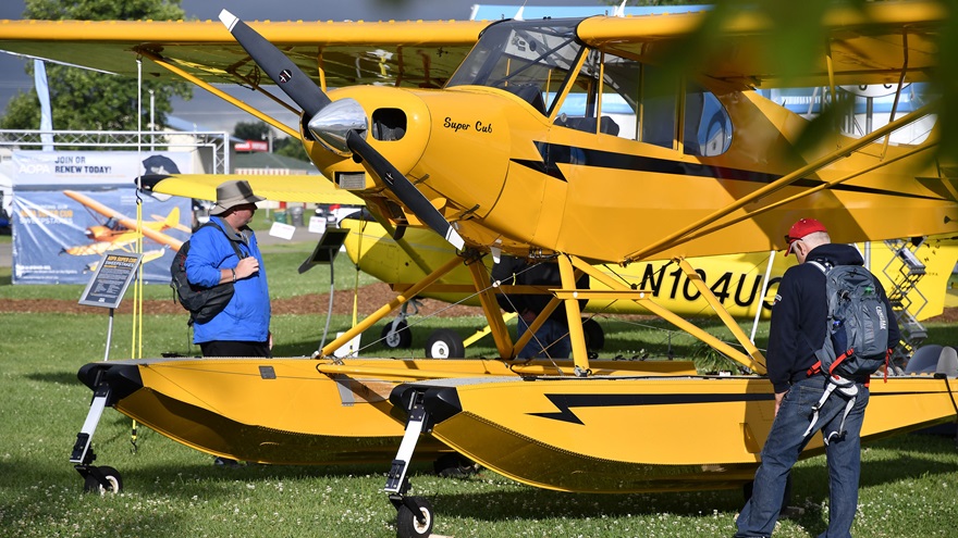 Attendees view a Piper Super Cub on amphibious floats in front of the AOPA exhibit tent July 24. It's standing in for the association's next sweepstakes airplane, which is currently being refurbished. Photo by David Tulis.