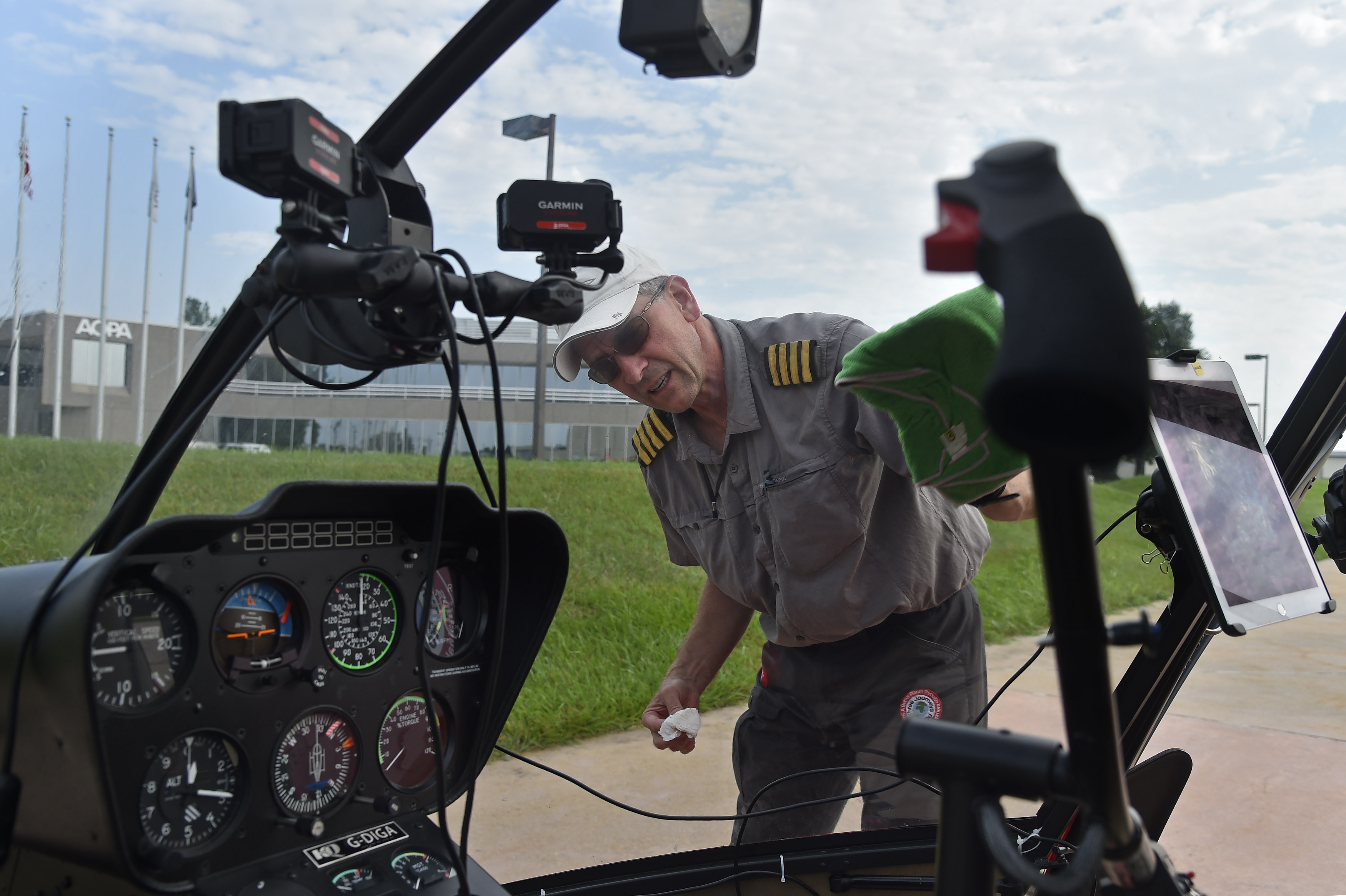 British helicopter pilot Peter Wilson cleans the windscreen during a stop at AOPA headquarters in Frederick, Maryland, as they entered the final quarter of a world-spanning flight in a Robinson R-66. Photo by David Tulis.