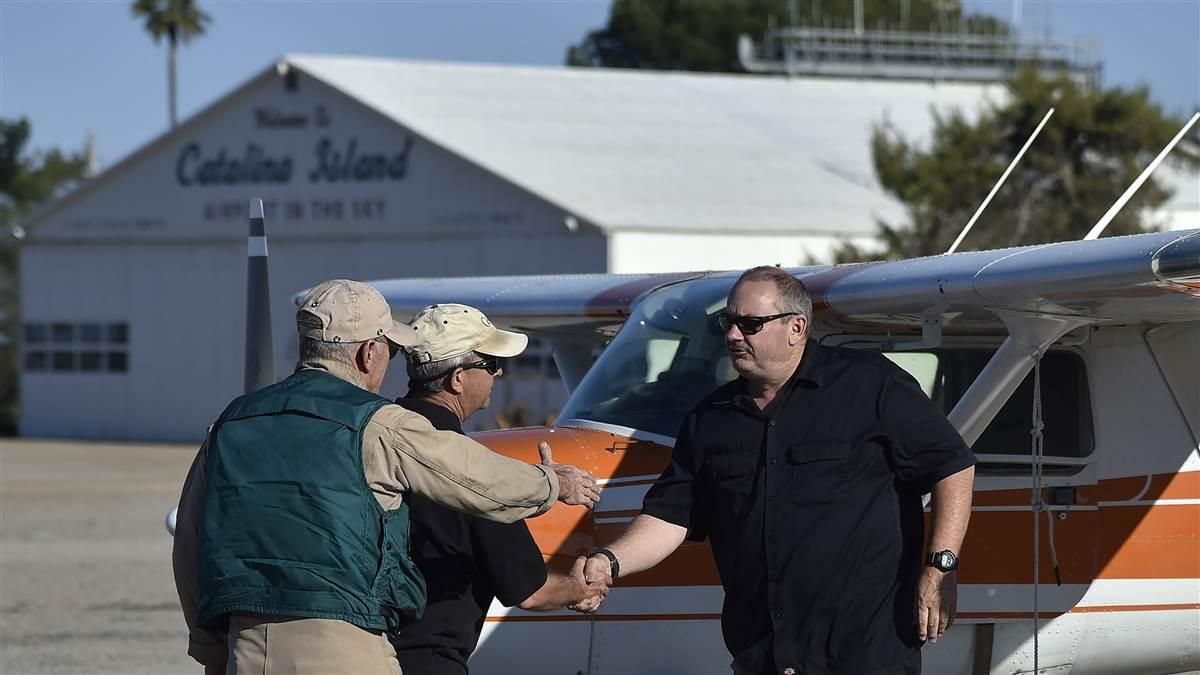 Cessna pilots Bob Lange, Mike Jesch, and Darrin Smith greet each other at Smith's Cessna 150. Smith removed a seat and slept in the Cessna rather than a tent. Photo by David Tulis.