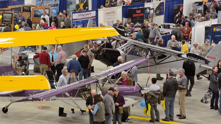 A purple-and-white Kitfox fit easily beneath the wing of a Quest Kodiak on amphibious floats, inside the Great Alaska Aviation Gathering's exhibit hall--a FedEx maintenance hangar at Ted Stevens Anchorage International Airport.