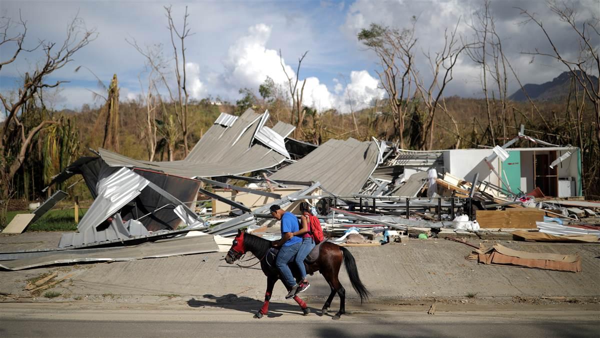 Local residents ride a horse by a destroyed building after Hurricane Maria in Jayuya, Puerto Rico, October 4, 2017. Photo by Carlos Barria, REUTERS.