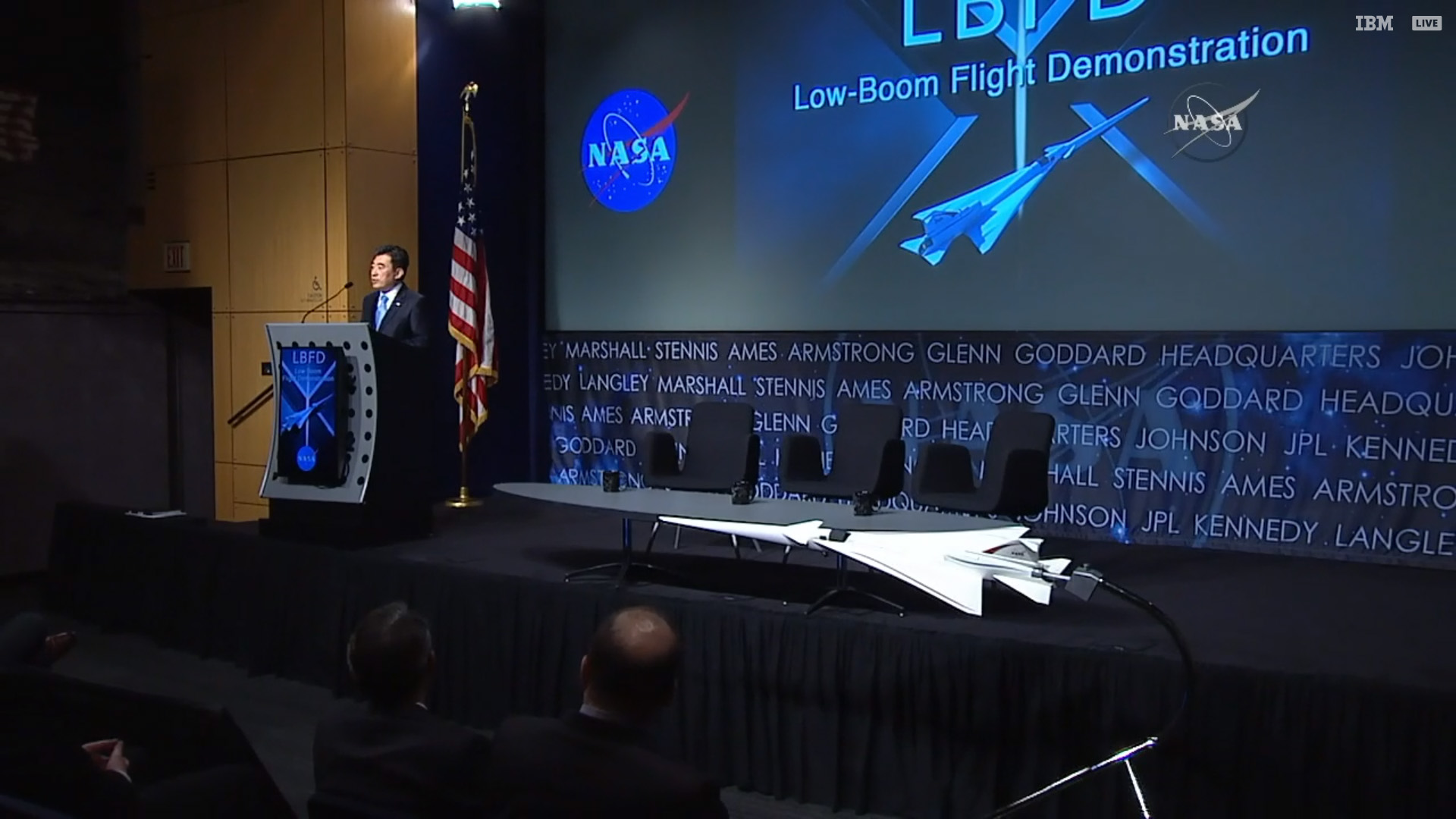 A scale model of the jet that will soon become an X-plane decorated the stage as NASA officials announced a contract award to Lockheed Martin on April 3. Photo from NASA broadcast. 