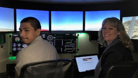 Bob Hoover Academy student Diego Merida and Deputy Superintendent of the Monterey County Office of Education Dr. Deneen Guss try out a new Redbird FMX full-motion simulator during a ribbon-cutting ceremony in California announcing a partnership between the aviation academy and Redbird Flight Simulations. Photo by Joey Colleran.