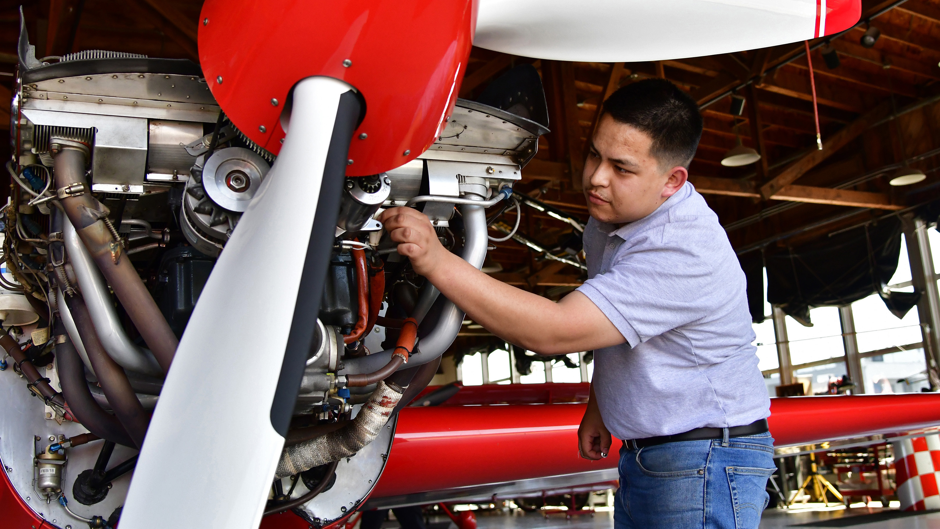 Aspiring aviation mechanic and Bob Hoover Academy graduate Martin Mendez checks the security of fittings on air show performer Sean D. Tucker's aerobatic Extra 300 at the Salinas Municipal Airport, May 11, 2018. Photo by David Tulis.