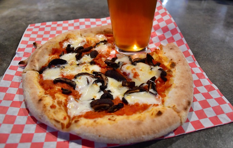 A fresh-baked pizza and a beer await a visitor to the Hunter-Gatherer Brewery inside the restored Curtiss-Wright Hangar at Jim Hamilton-L.B. Owens Airport near downtown Columbia, South Carolina. Photo by David Tulis.