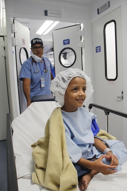 Getting down to business—staff preps a young patient in Bangladesh for surgery and a follow-up exam on an infant. Photo courtesy of Celia Yeung/Orbis.