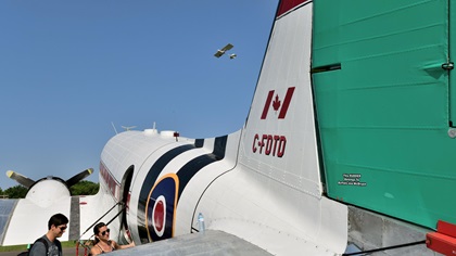 C-FDTD, the DC-3/C-47 restored by Mikey McBryan's Plane Savers project, journeyed to EAA AirVenture in Oshkosh, Wisconsin. An ultralight takes off above the airplane, which arrived at Wittman Field on Tuesday. Photo by Mike Collins.