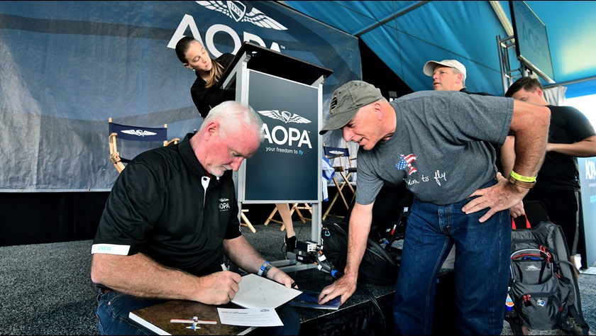 After his EAA AirVenture Oshkosh Town Hall presentation, AOPA President Mark Baker, left, signs a copy of "Freedom to Fly: AOPA and the History of General Aviation in America" for David Pfeiffer of Indianapolis, Indiana. "That is an excellent book. I read it all the way through," Pfeiffer said. Photo by Mike Collins.