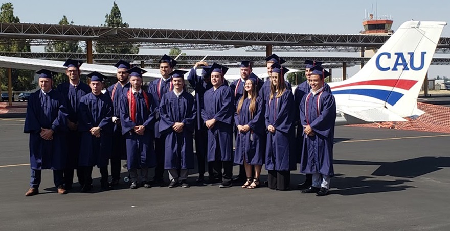 The inaugural class of California Aeronautical University graduates wears caps and gowns during a photo shoot near a Cessna 172 in Bakersfield, California. Photo courtesy of California Aeronautical University.