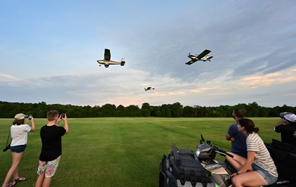 Young aviators capture the moment as a flight of three aircraft make a low approach during sunset flights above the 7,000-foot-long grass landing strip. Photo by David Tulis.