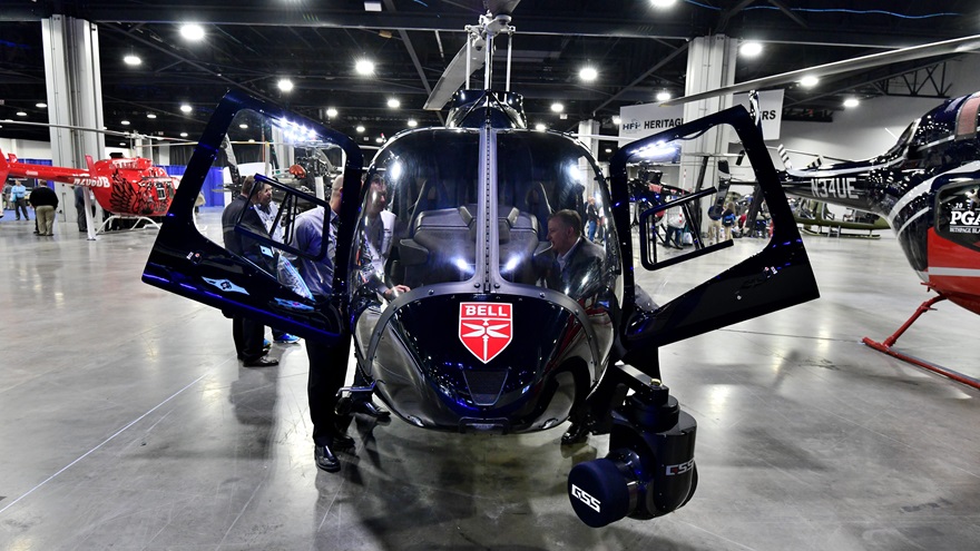 Vistors to HAI Heli-Expo 2019 examine a Bell 205 with a gyrostabilized camera mounted on the nose. Photo by Mike Collins.
