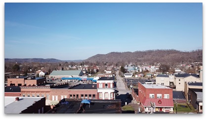 Aerial shot over small town, hills in background.