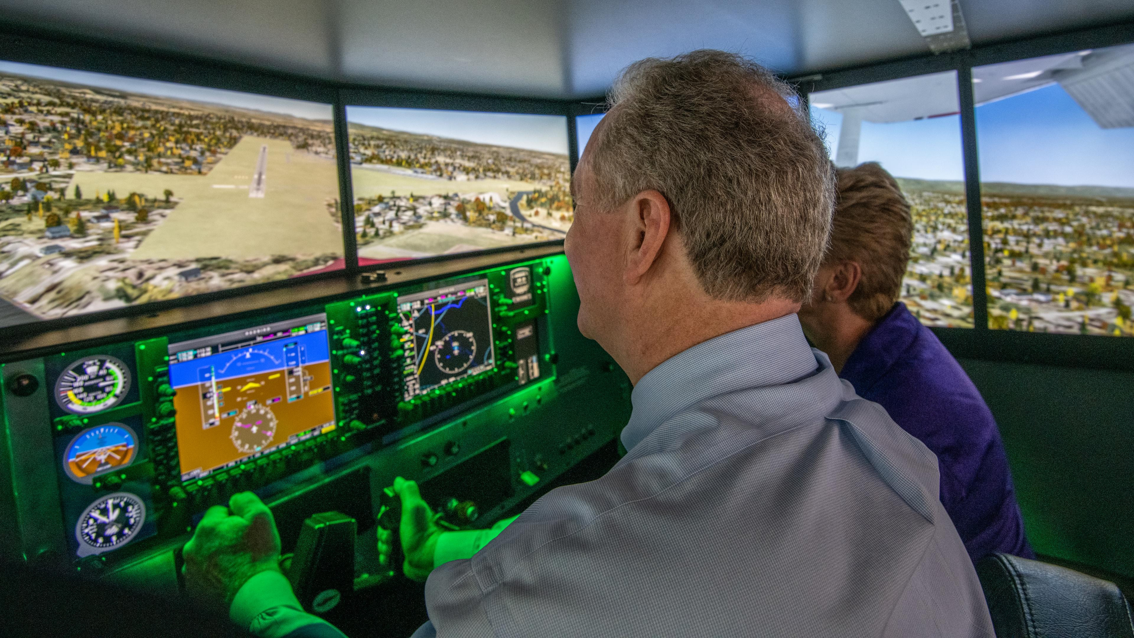 U.S. Sen. Chris Van Hollen (D-Md.), left, flies a Redbird simulator under the tutelage of Luz Beattie, AOPA's director of flight operations. Van Hollen visited AOPA's headquarters May 20. Photo by Mike Collins.