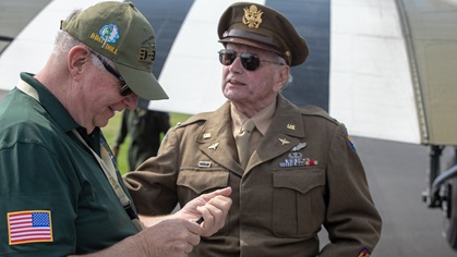 Retired Lt. Col. Dave Hamilton, 96, the last surviving member of a group of 20 pathfinders who dropped paratroopers hours ahead of the main invasion, chats with a <em>D-Day Doll</em> crew member at Waterbury-Oxford Airport on May 17. Photo by Jim Moore.