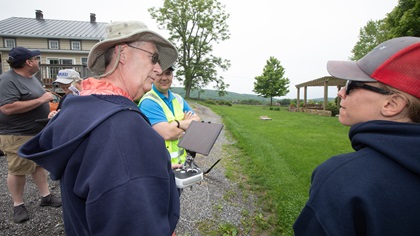 Engineer Michael Whitcomb, left, consults with his teammate, retired U.S. Marine Corps Capt. Shelby Goudy, during a mapping exercise led by DARTdrones Chief Flight Instructor Colin Romberger (background) on May 11. The mapping and modeling workshop included classroom sessions at AOPA headquarters in Frederick, and hands-on flight training at a farm a few miles southwest, outside of controlled airspace. Photo by Jim Moore.