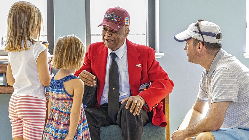 Former U.S. Navy pilot Chris Demay of Annapolis and his daughters Dara and Bela speak with Tuskegee Airmen retired U.S. Army Col. William A. DeShields. Photo by Alton K. Marsh.