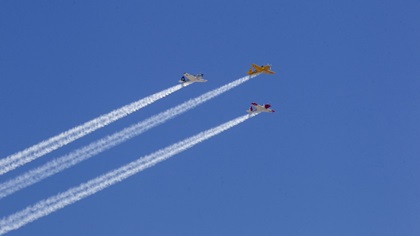 A trio of Beechcraft T-34s in vintage military trainer colors performs a flyover with “smoke on” for hospital workers in San Diego. One of the T-34 pilots, George Watson, had a special connection with the medical teams he was saluting: A successful heart surgery in 2018 at Scripps Memorial Hospital helped him return to the air. Photo courtesy of Phil Kendro.