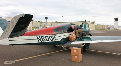 Pilot Bruce Phillips unloads donated personal protective equipment from his airplane after Aerobridge members transported about 3,000 face shields for healthcare workers from California to Walla Walla, Washington. Photo courtesy of Bill Herrington.                                                                                                                                         