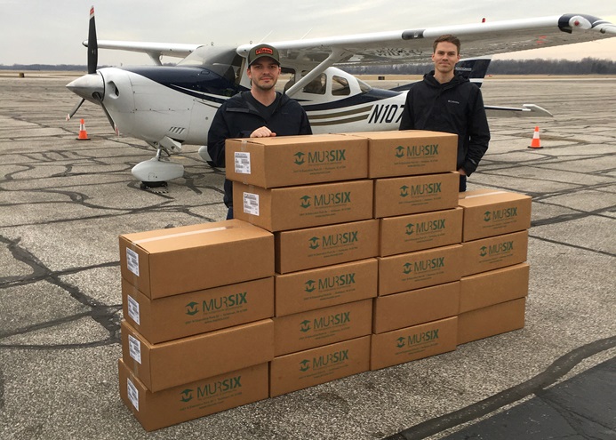 Michigan Seaplane flight school instructors Nick Hall and Mike Mato stack boxes of medical face shields fabricated by an Indiana auto parts manufacturer before flying them to a Michigan hospital in a Cessna 206. Flight school owner Cran Jones organized the effort through his contacts in the automobile parts supplier community. Photo courtesy of Nick Hall and Mike Mato.
