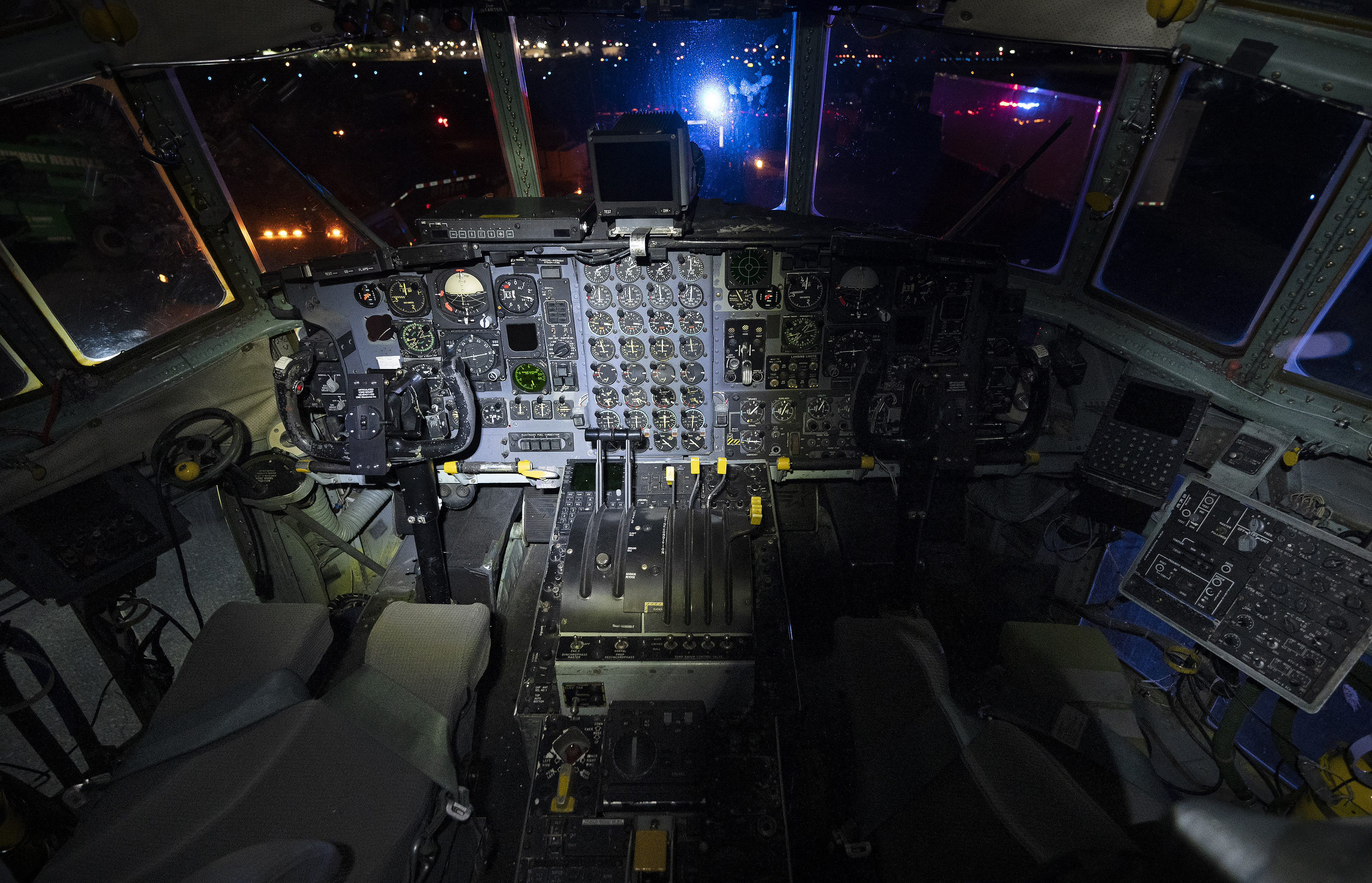 The lights of a police escort are reflected in the cockpit of a retired U.S. Air Force Lockheed C-130H Hercules aircraft with more than 24,000 flight-hours logged before the multiengine aircraft is moved on city streets from Frederick Municipal Airport to Fort Detrick, a U.S. Army Medical Command Station, in Frederick, Maryland, March 14. Photo by David Tulis.