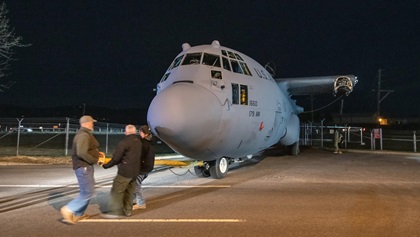 With the Hercules being pulled backwards through the gate to Fort Detrick's Area B, crewmembers use the C-130's towbar to steer the aircraft. Photo by Mike Collins.