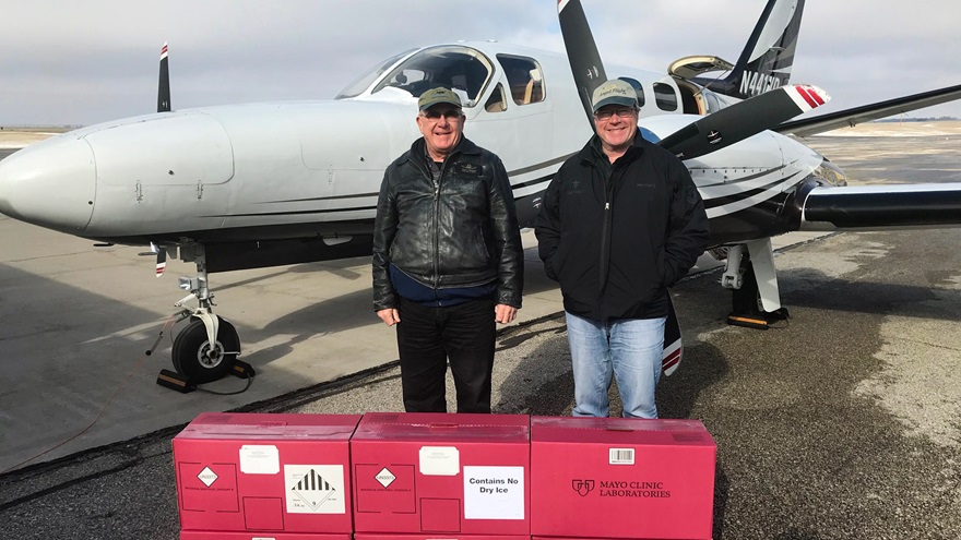 Pilots Hobie Tomlinson (left) and Kirk Walters (right) stand with packages of COVID-19 test kits being taken to the Mayo Clinic by the daily general aviation shuttle established by Walters. His Cessna 441 Conquest II flew 11 missions over the same number of days and helped carry over 5,000 test kits between the University of Vermont Medical Center and the Mayo Clinic. Photo courtesy of Kirk Walters.