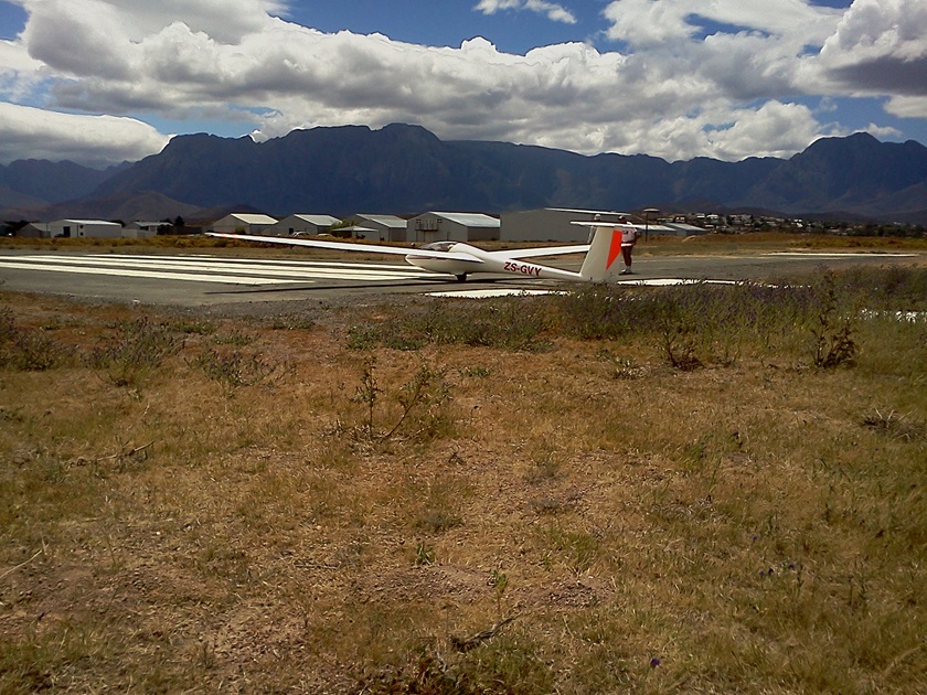 A Cape Gliding Club glider waits for the signal before being winched skyward at Worcester Airport, deep in wine country, some two hours from Cape Town, South Africa. The club facilities include a clubhouse, pool, individually owned weekend "huts" and hangars for the tow plane, and numerous club and club member aircraft residing on the airfield. Photo by Amy Laboda.